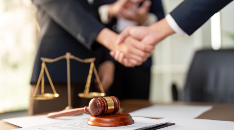 Handshake between legal professionals with a judge gavel and justice scale symbolizing trust, legal support, and professional legal services.