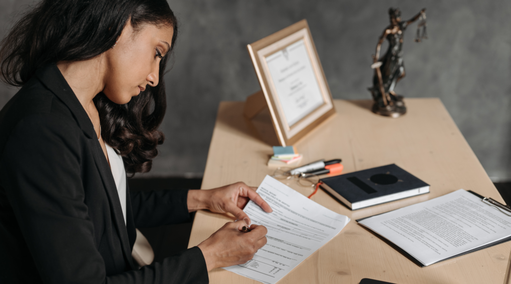 Female legal professional reviewing and signing legal documents in an office environment.